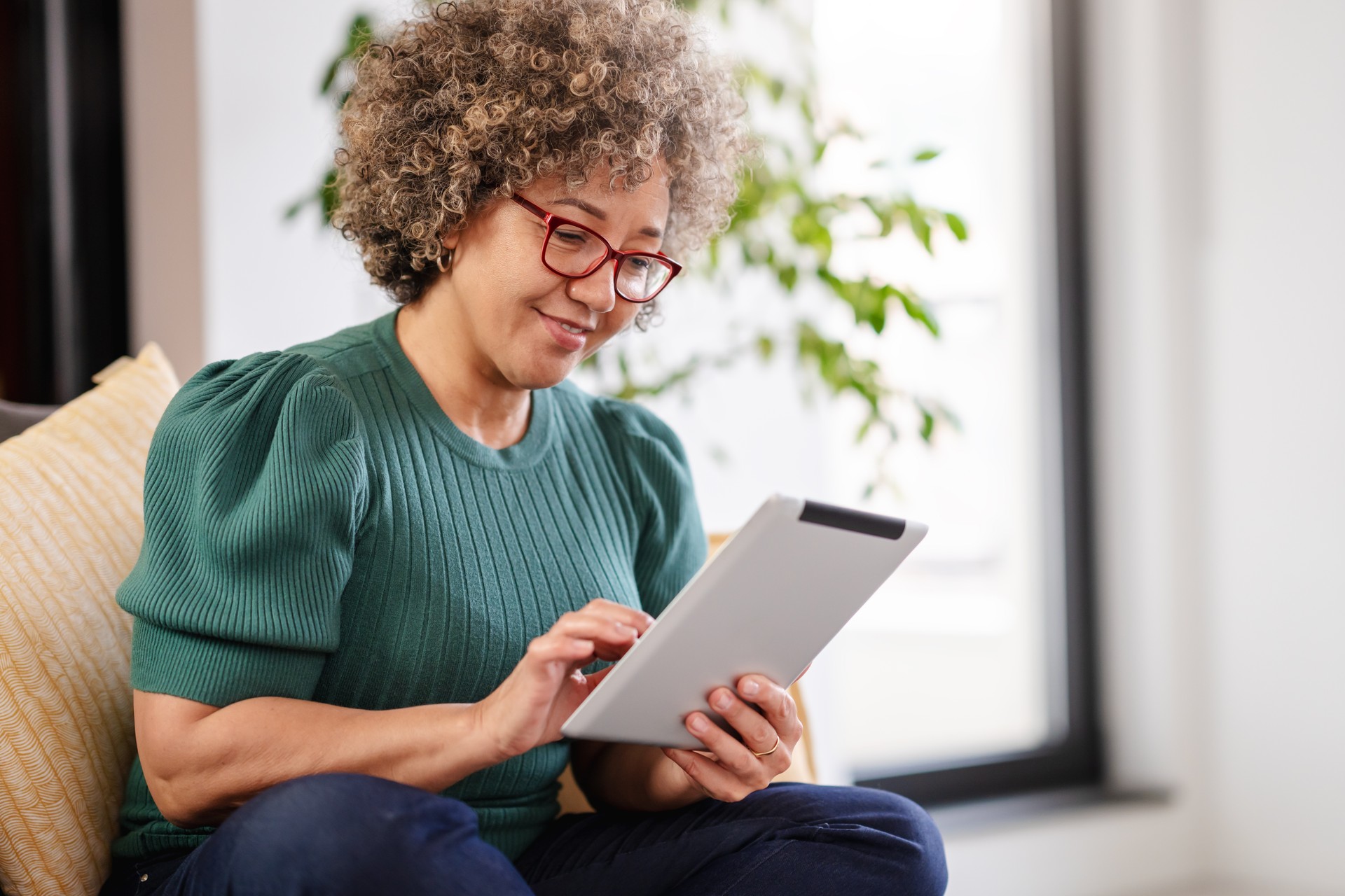 Beautiful middle-aged woman using a computer tablet to read a book and surf internet